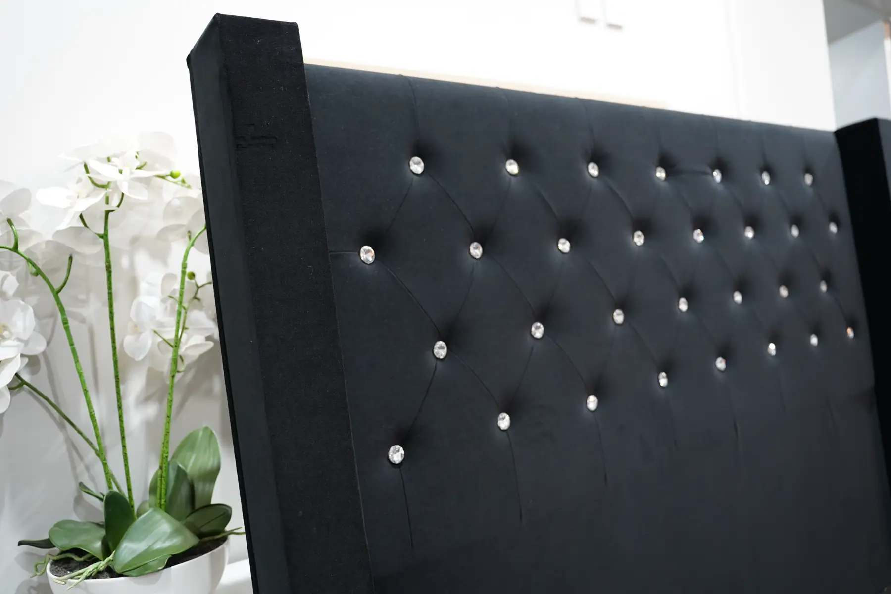 The black crystal-buttoned headboard from an angle, showing the forward wings.