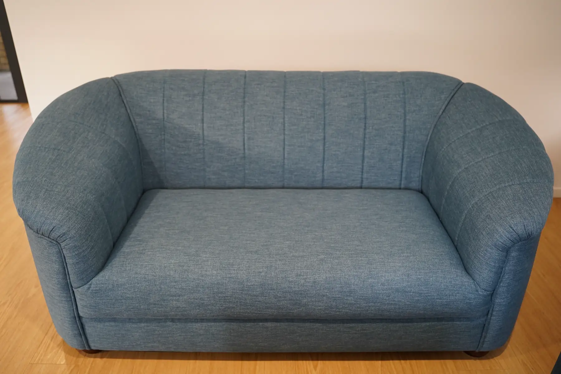 A two-seat sofa in blue-grey cloth with a fluted back and rounded arms.