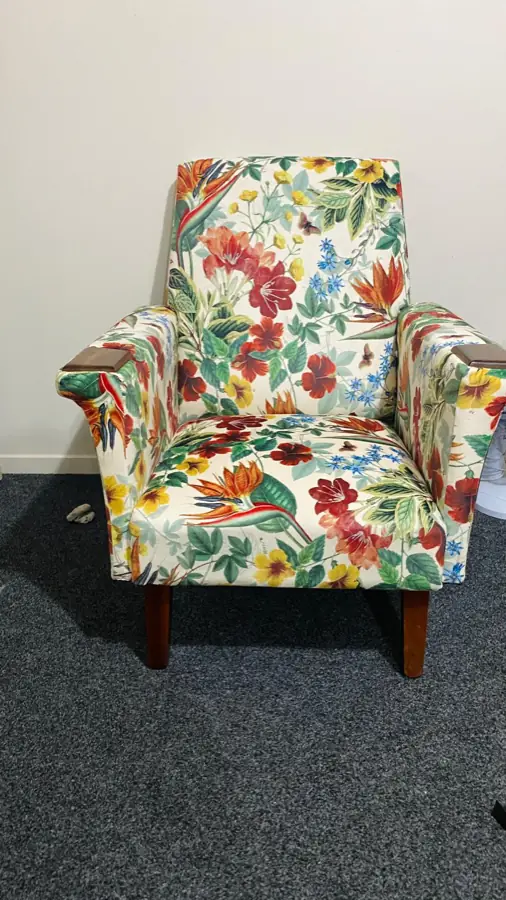 The botanical-print armchair from the front, on dark timber legs.