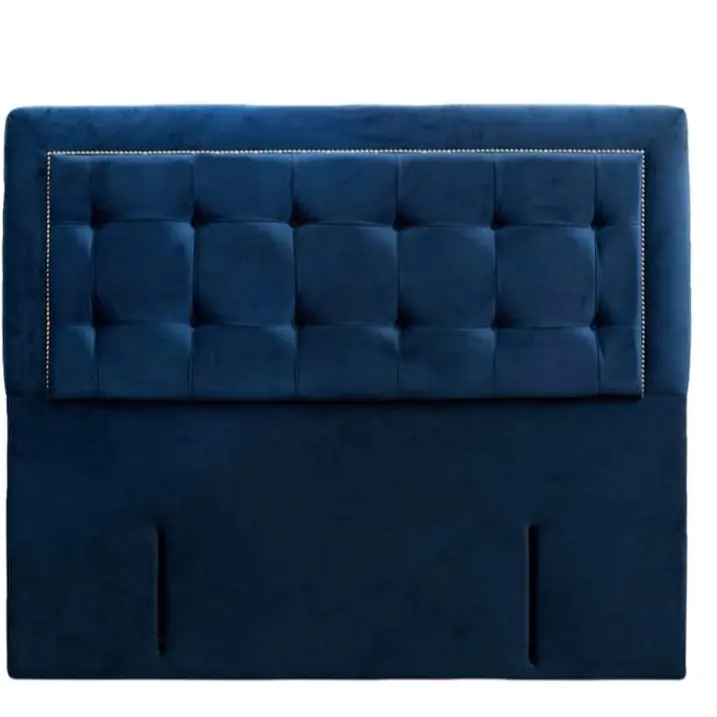 A deep navy velvet headboard, buttoned and bordered with a line of studs.