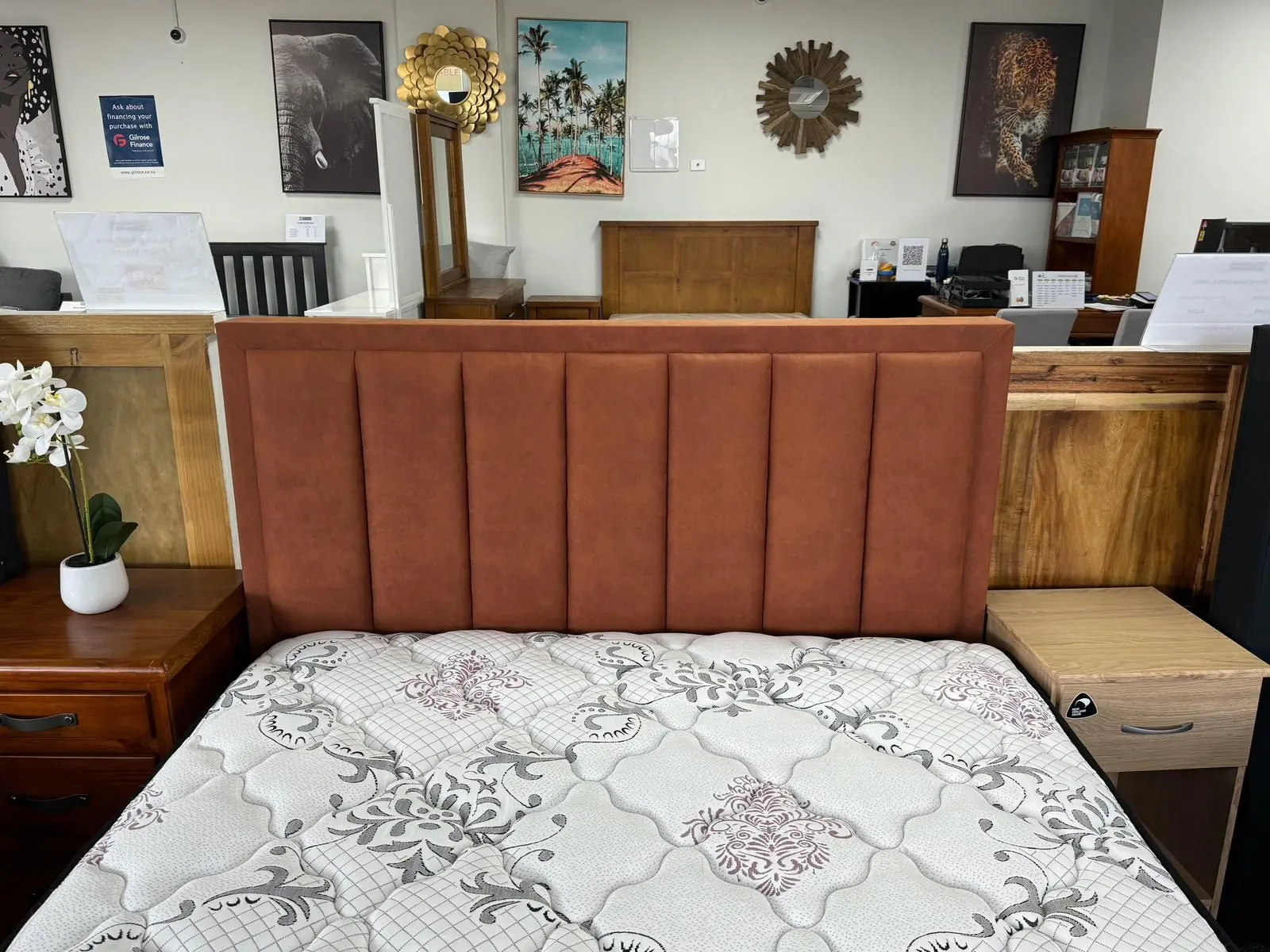 A tan fluted headboard above a bed in a showroom, flanked by timber bedsides.